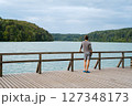 Young man standing near lake, view from back. Recreation in nature concept Young man standing near lake, view from back. Recreation in nature concept 127348173