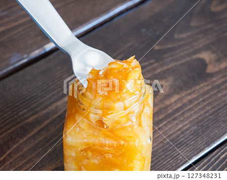 柑橘の果皮と果実を甘く煮て作ったマーマレード・ジャム。スプーンでジャムを掬っている様子。 127348231