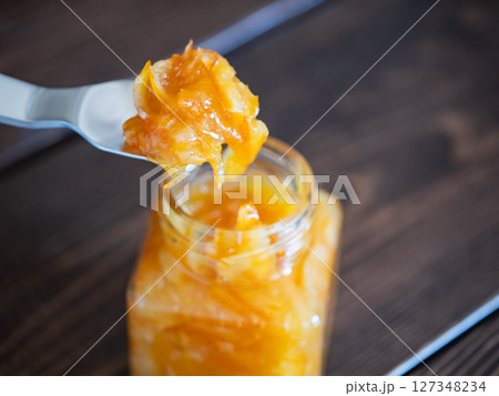 柑橘の果皮と果実を甘く煮て作ったマーマレード・ジャム。スプーンで掬ったジャム。 127348234