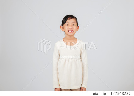 A cute kid girl smiles, showing a missing tooth. The dentist advises on tooth loss and dental care for children with gaps from lost baby teeth. 127348287