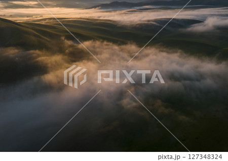 thick morning clouds over a hilly valley thick morning clouds over a hilly valley 127348324