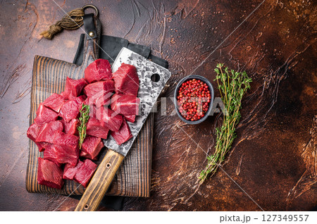 Diced Raw Boar meat, uncooked Game Meat on butcher cutting board. brown background. top view Diced Raw Boar meat, uncooked Game Meat on butcher cutting board. brown background. top view 127349557
