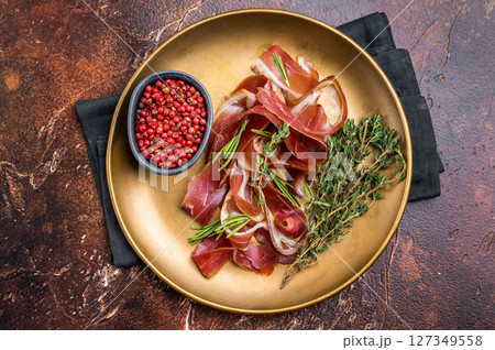 Cured duck fillet meat slices, magret smoked poultry on a plate. brown background. top view Cured duck fillet meat slices, magret smoked poultry on a plate. brown background. top view 127349558