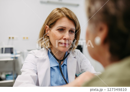 Geriatrician doctor examining elderly patient with stethoscope. Geriatrician doctor examining elderly patient with stethoscope. 127349810