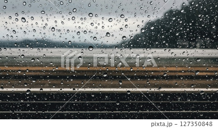 Raindrops on Train Window with Blurred Passing Scenery 127350848