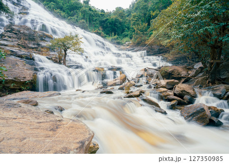 Beautiful waterfall with a lush green forest in the background. The water is flowing down the rocks and creating a beautiful scene. Sustainable waterfall in lush forest promoting water sustainability. 127350985