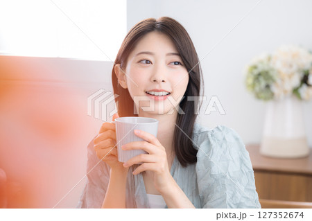 部屋で飲み物を飲んでリラックスするかわいい若い女性 のんびりティータイム 部屋で飲み物を飲んでリラックスするかわいい若い女性 のんびりティータイム 127352674