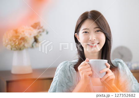 部屋で飲み物を飲んでリラックスするかわいい若い女性　のんびりティータイム 127352682