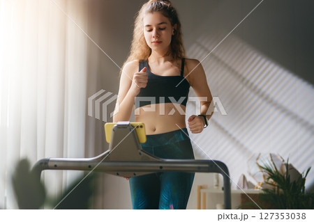 Young woman running on a treadmill indoors 127353038