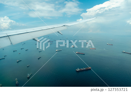 Airplane arriving over sea with cargo ships in Singapore 127353721
