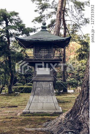 Aged Japanese lantern structure in a mossy garden setting with muted tones and soft lighting 127353932