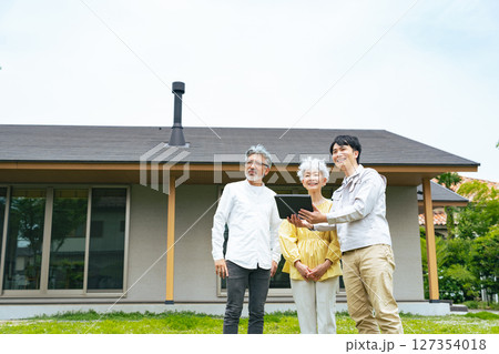 住宅の前で説明する男性作業員とシニアカップル 住宅の前で説明する男性作業員とシニアカップル 127354018