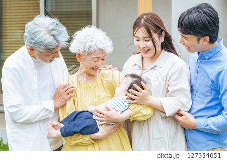 笑顔で赤ちゃんを囲む三世代家族 笑顔で赤ちゃんを囲む三世代家族 127354051