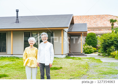 笑顔で住宅の前に立つシニアカップル 127354063