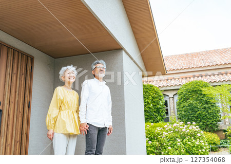 笑顔で住宅の前に立つシニアカップル 127354068