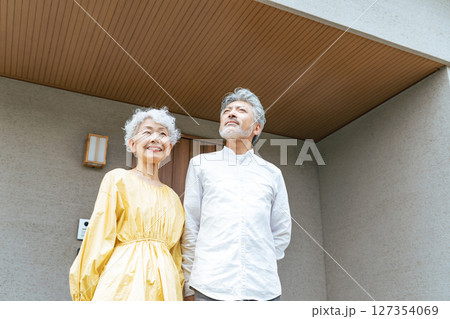 笑顔で住宅の前に立つシニアカップル 笑顔で住宅の前に立つシニアカップル 127354069