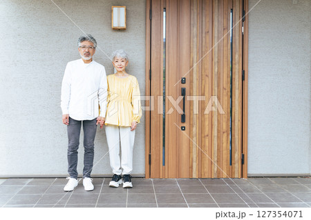 笑顔で住宅の前に立つシニアカップル 笑顔で住宅の前に立つシニアカップル 127354071