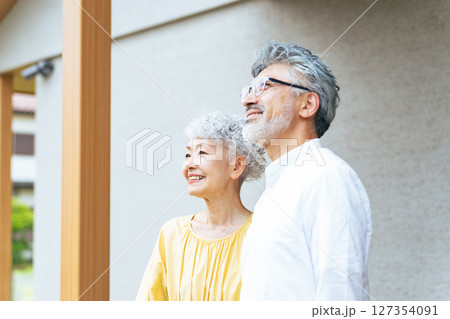 笑顔で住宅の前に立つシニアカップル 127354091