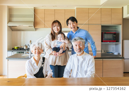 笑顔で赤ちゃんを囲む三世代家族 笑顔で赤ちゃんを囲む三世代家族 127354162