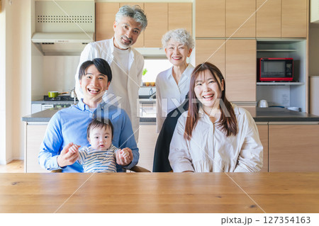 笑顔で赤ちゃんを囲む三世代家族 127354163
