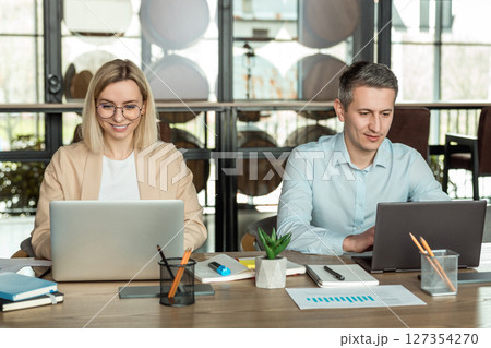 Colleagues sitting at the table in the office and discussing project details Colleagues sitting at the table in the office and discussing project details 127354270