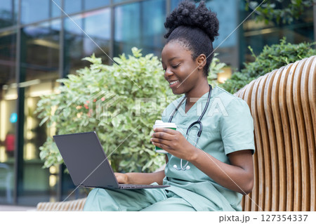 African american young doctor sitting on the bench and having coffee 127354337