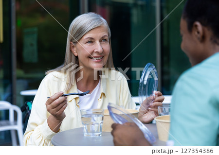 Nurse and a patient on a wheelchair having lunch together and talking Nurse and a patient on a wheelchair having lunch together and talking 127354386