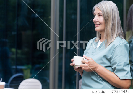 Mature caucasian female doctor having coffee and looking relaxed 127354423
