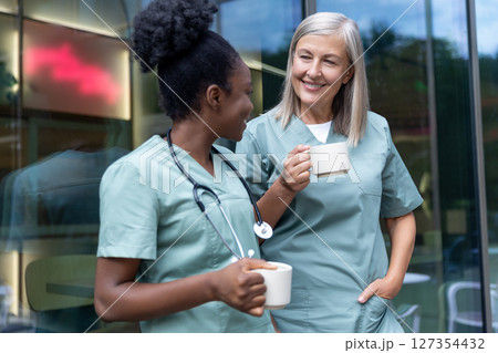 Two female doctors with cups with coffee in the elevator talking 127354432