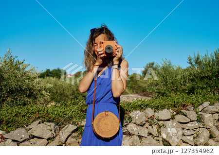 Woman taking photo with instant camera in rural landscape Woman taking photo with instant camera in rural landscape 127354962
