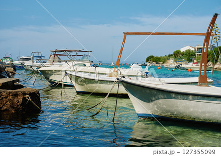 Anchored motor boats moored in sea water near dock Anchored motor boats moored in sea water near dock 127355099