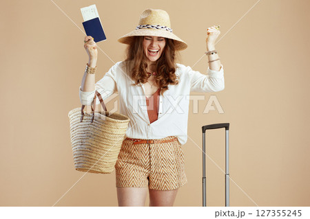 smiling elegant woman in blouse and shorts rejoicing on beige 127355245