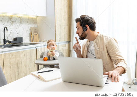 Young father working from home, his baby boy playing next to him 127355605