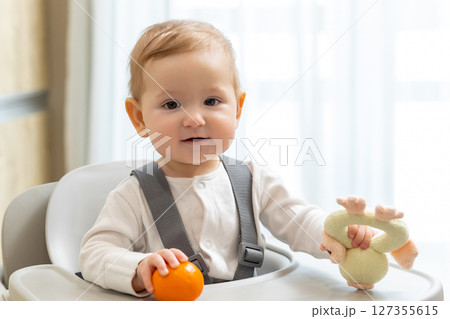 Cute small baby boy sitting in his chair and playing 127355615