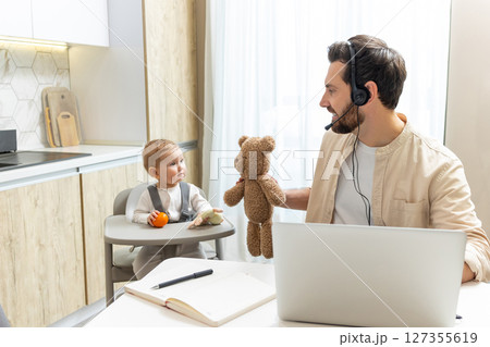 Young man having a call on internet while doing babysitting Young man having a call on internet while doing babysitting 127355619