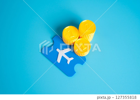 Stacks of coins and a plane ticket. Save on flights. Smart budgeting, flight discounts, and saving money on travel expenses through careful planning. 127355818