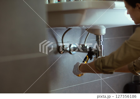 Plumber under Sink with Wrench 127356186