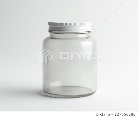Clear glass jar with white lid placed on a neutral background for storage and organization Clear glass jar with white lid placed on a neutral background for storage and organization 127356286