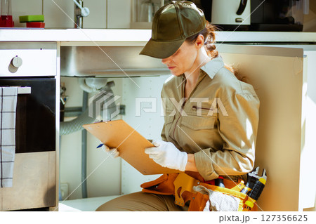 Plumber Inspecting Under Kitchen Sink 127356625