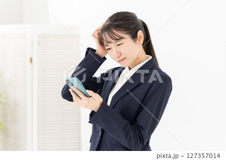 ビジネスウーマン　若い女性　スマホ　悩む 127357014