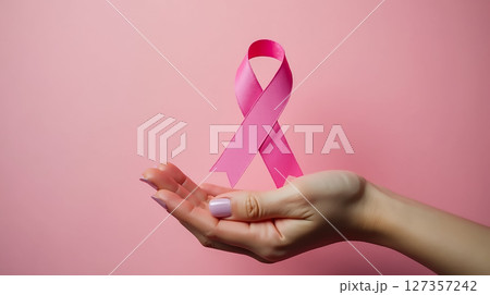 Support for breast cancer awareness represented by a pink ribbon held in an open hand against a soft pink background Support for breast cancer awareness represented by a pink ribbon held in an open hand against a soft pink background 127357242
