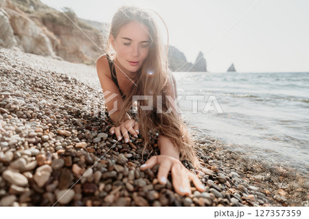 Woman Reaching for the Ocean on a Pebble Beach Woman Reaching for the Ocean on a Pebble Beach 127357359