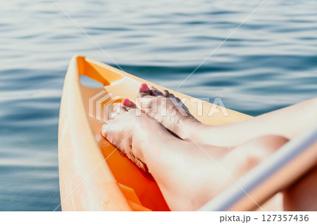 Feet Kayaking Paddle Relaxation - Closeup of feet in kayak on water during a relaxing kayaking experience. Feet Kayaking Paddle Relaxation - Closeup of feet in kayak on water during a relaxing kayaking experience. 127357436