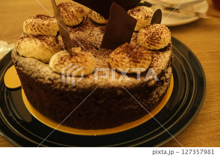 黒いプレートに盛られたチョコレートケーキ、マカロンとナッツのトッピング 127357981