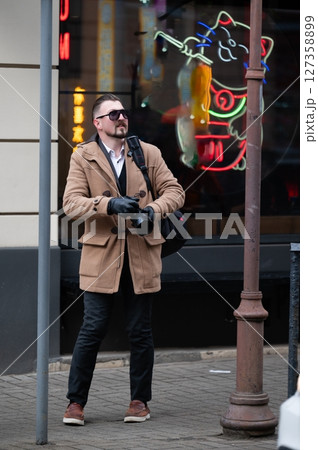 Captured in urban exploration, a stylish photographer admires neon cat art while searching for the perfect shot during a chilly afternoon in the bustling city Captured in urban exploration, a stylish photographer admires neon cat art while searching for the perfect shot during a chilly afternoon in the bustling city 127358899