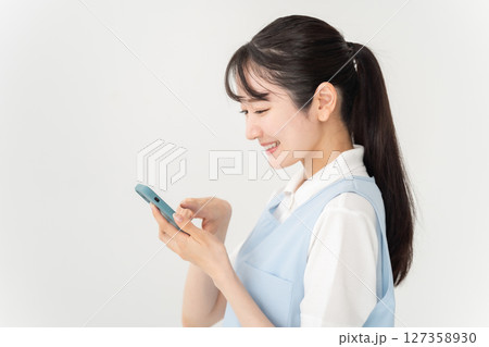 エプロンの若い女性　スマホ 127358930