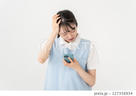 エプロンの若い女性　スマホ　トラブル 127358934