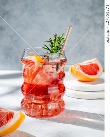 Lemonade with grapefruit, rosemary and ice in a glass on a light background with sunlight. Lemonade with grapefruit, rosemary and ice in a glass on a light background with sunlight. 127359271