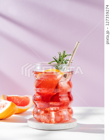 Refreshing mocktail with grapefruit, rosemary and ice in a glass on a white pink background Refreshing mocktail with grapefruit, rosemary and ice in a glass on a white pink background 127359274