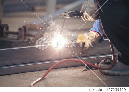 Construction Worker hands using Welding machinery iron metal sparking. Men hands wear protective glove Hot flame metal work cutting fire iron workshop. Locksmith use Welding machine cut metal process Construction Worker hands using Welding machinery iron metal sparking. Men hands wear protective glove Hot flame metal work cutting fire iron workshop. Locksmith use Welding machine cut metal process 127359339